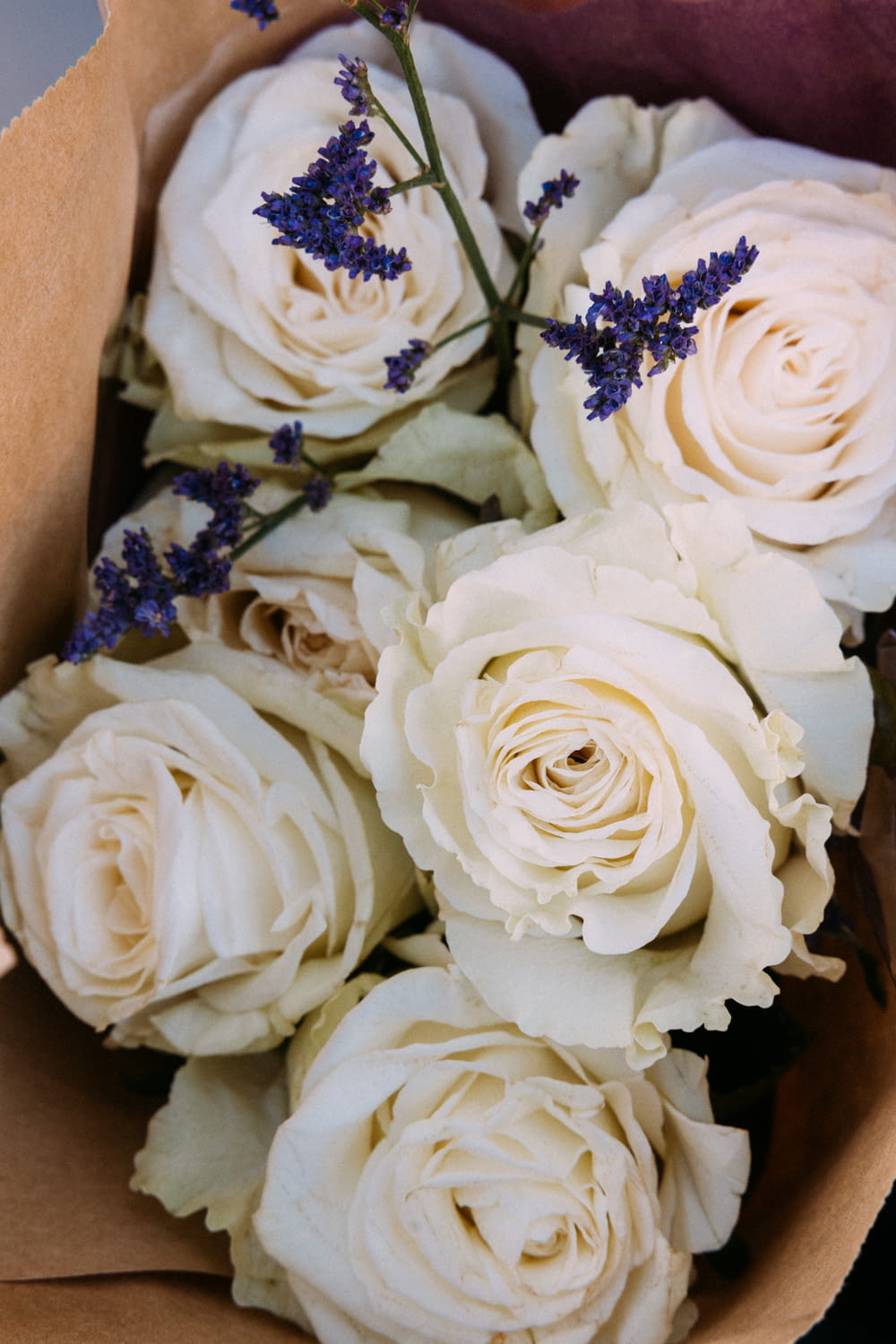 a bouquet of white roses in a brown paper bag