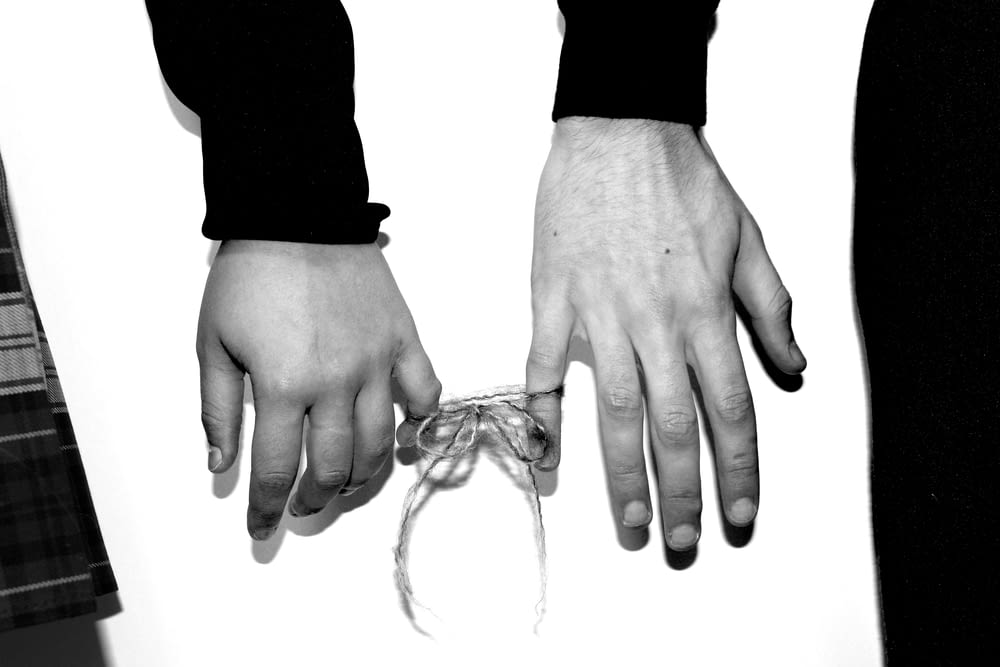 two hands holding a string tied to a tie