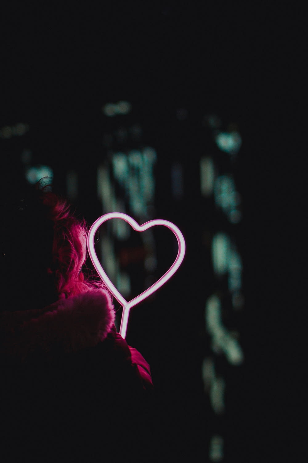 a person holding a heart shaped object in the dark