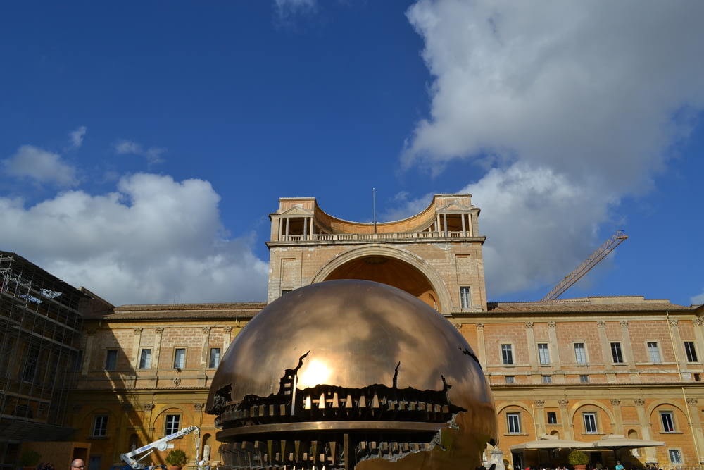 a large metal ball sitting in front of a building