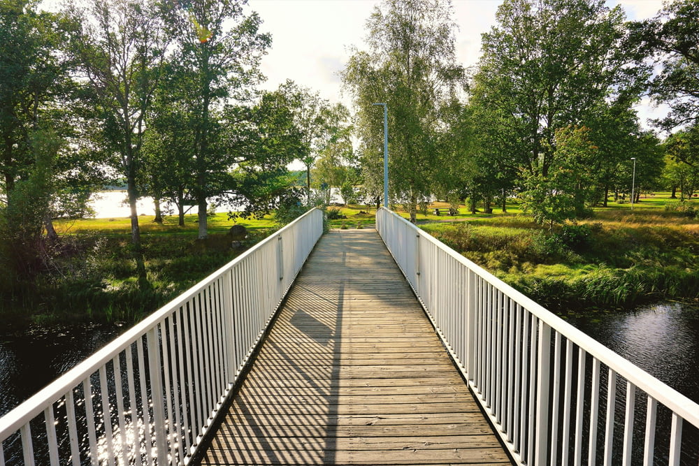a wooden bridge over a river with trees in the background
