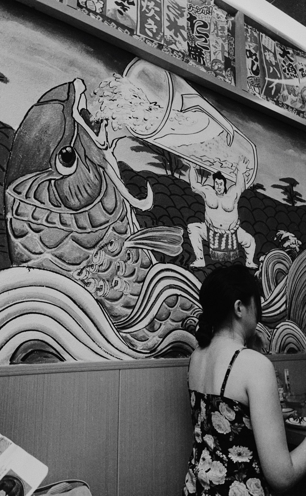 a woman standing in front of a wall with a painting on it
