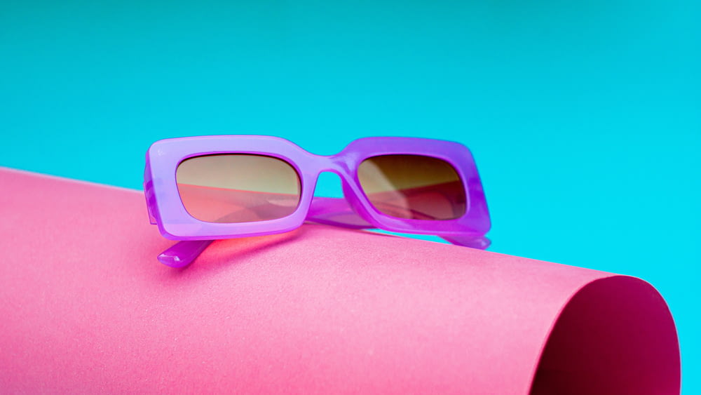 a pair of sunglasses sitting on top of a pink tube