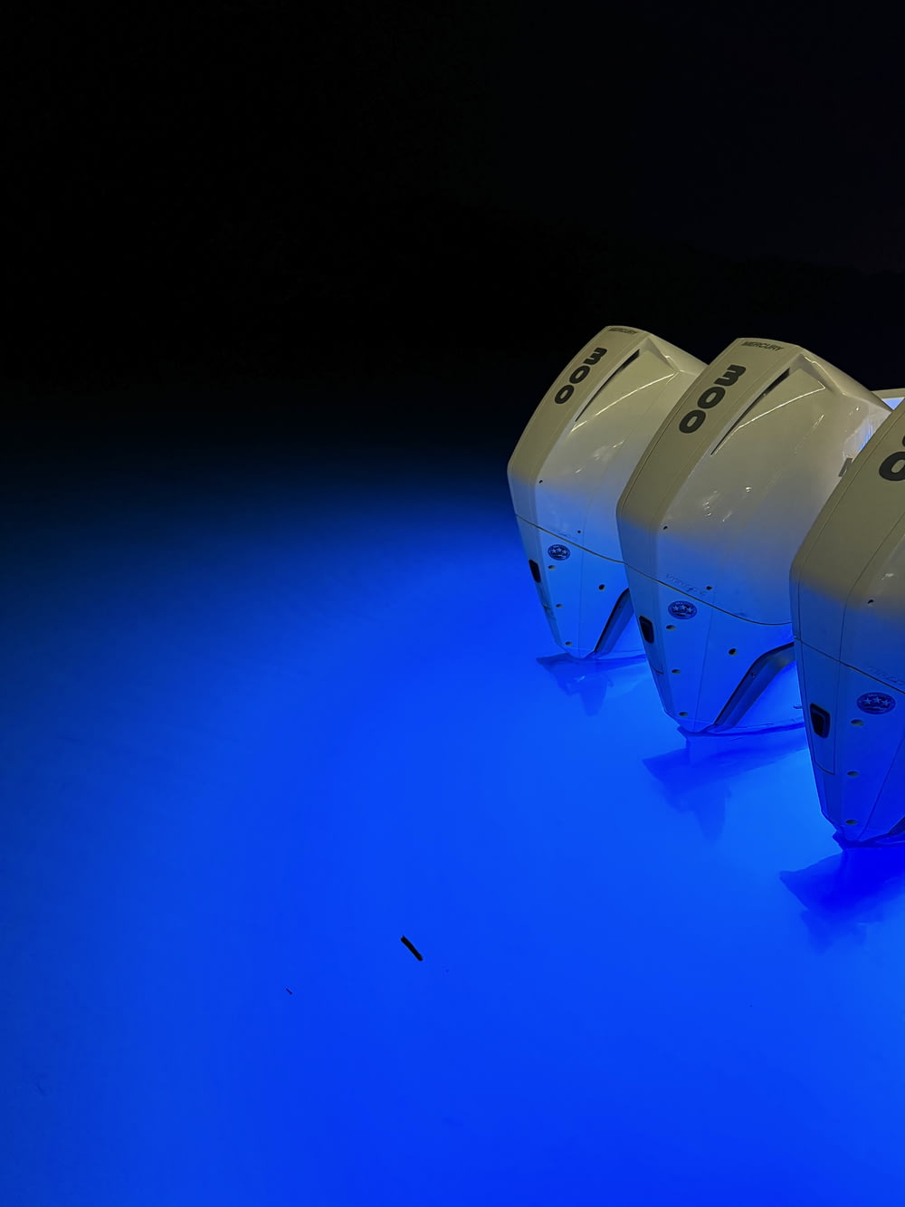 a row of white toilets sitting on top of a blue floor