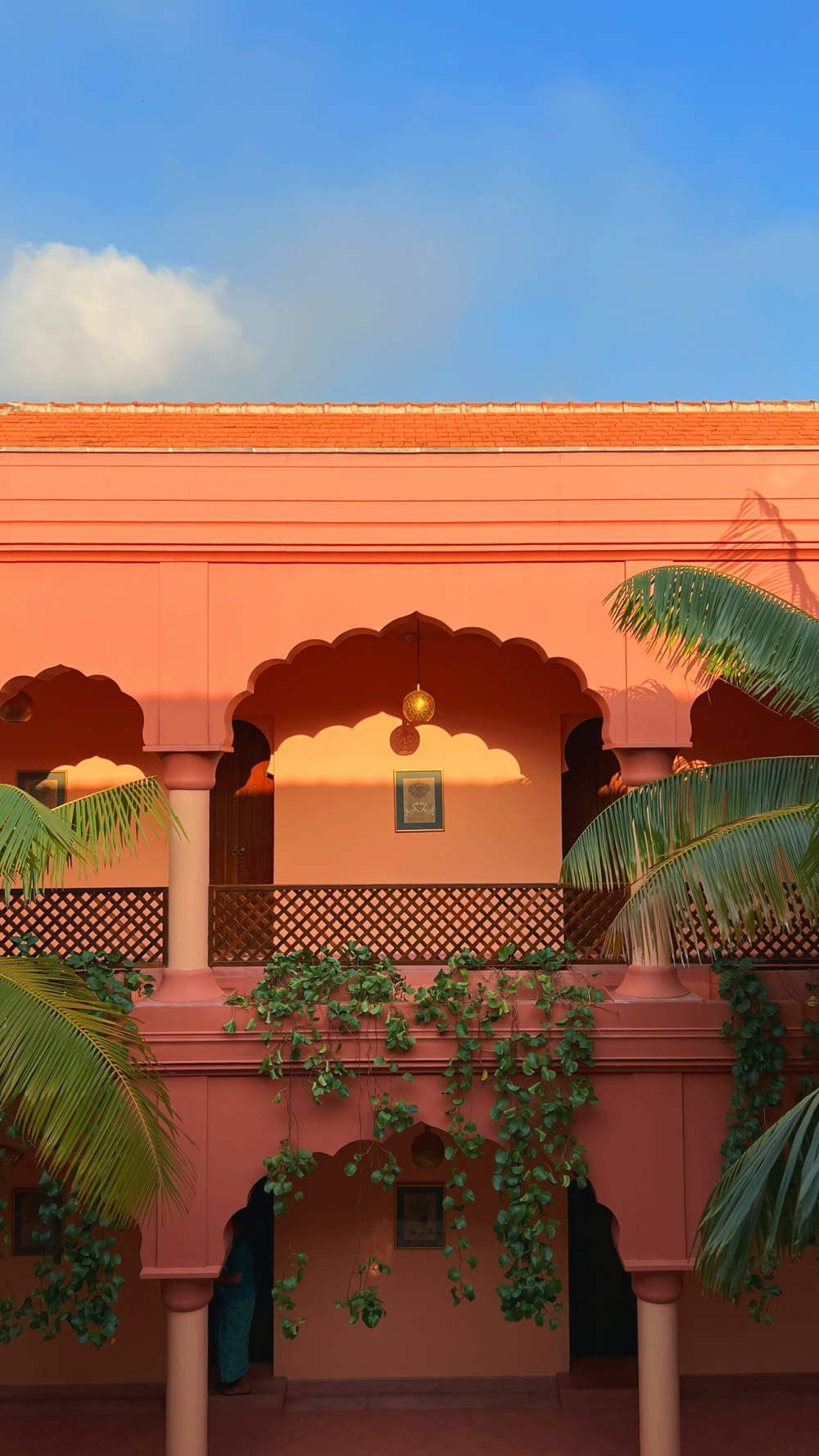 a pink building with a balcony and palm trees