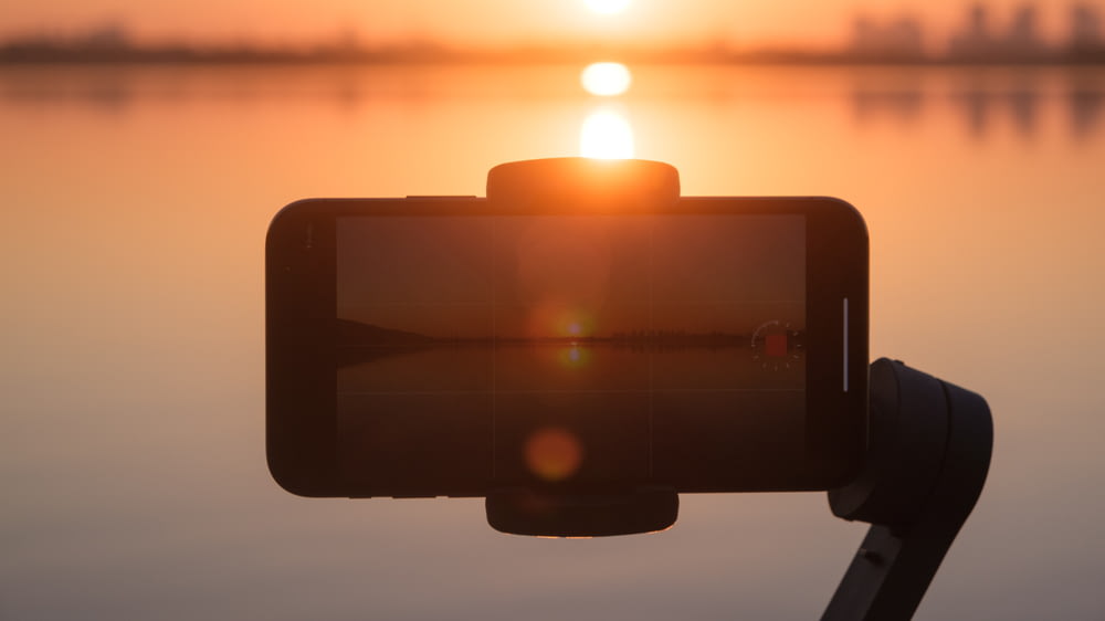 a close up of a camera with a sunset in the background