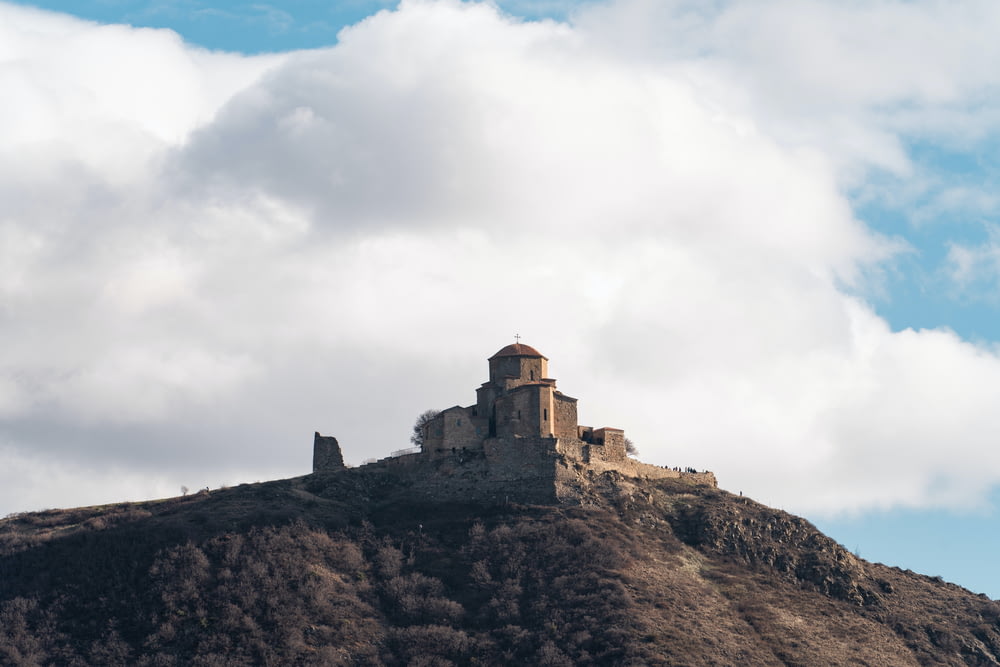 un castello seduto in cima a una collina sotto un cielo nuvoloso