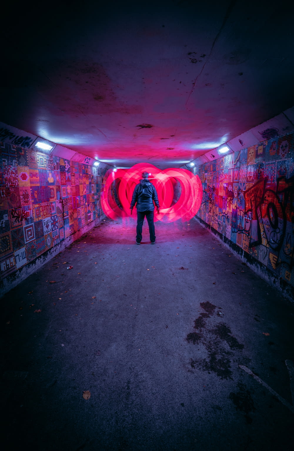 a person standing in a tunnel with graffiti on the walls