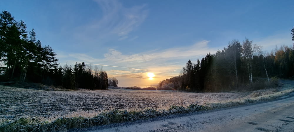 the sun is setting over a frosty field