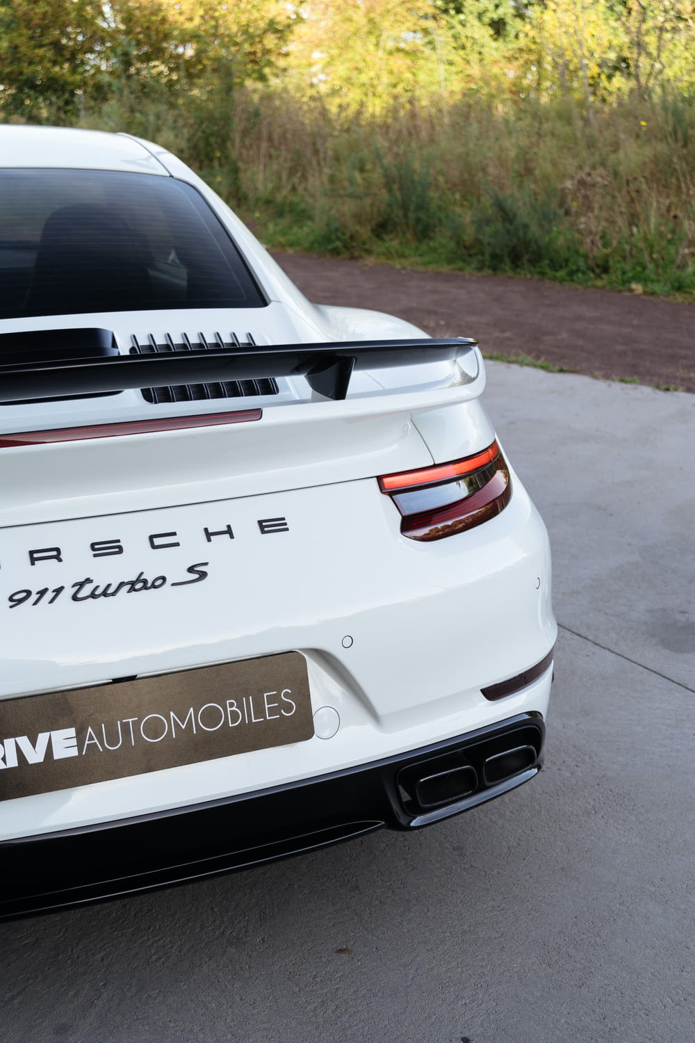 the back of a white porsche car parked in a driveway