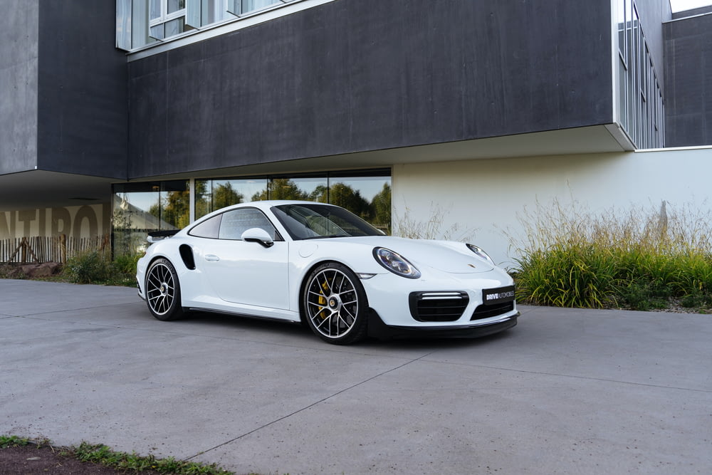 a white porsche parked in front of a building
