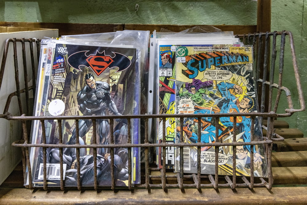 a metal basket filled with comic books on top of a table