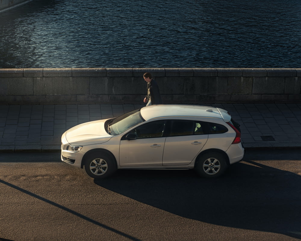 une personne debout sur le toit d’une voiture blanche