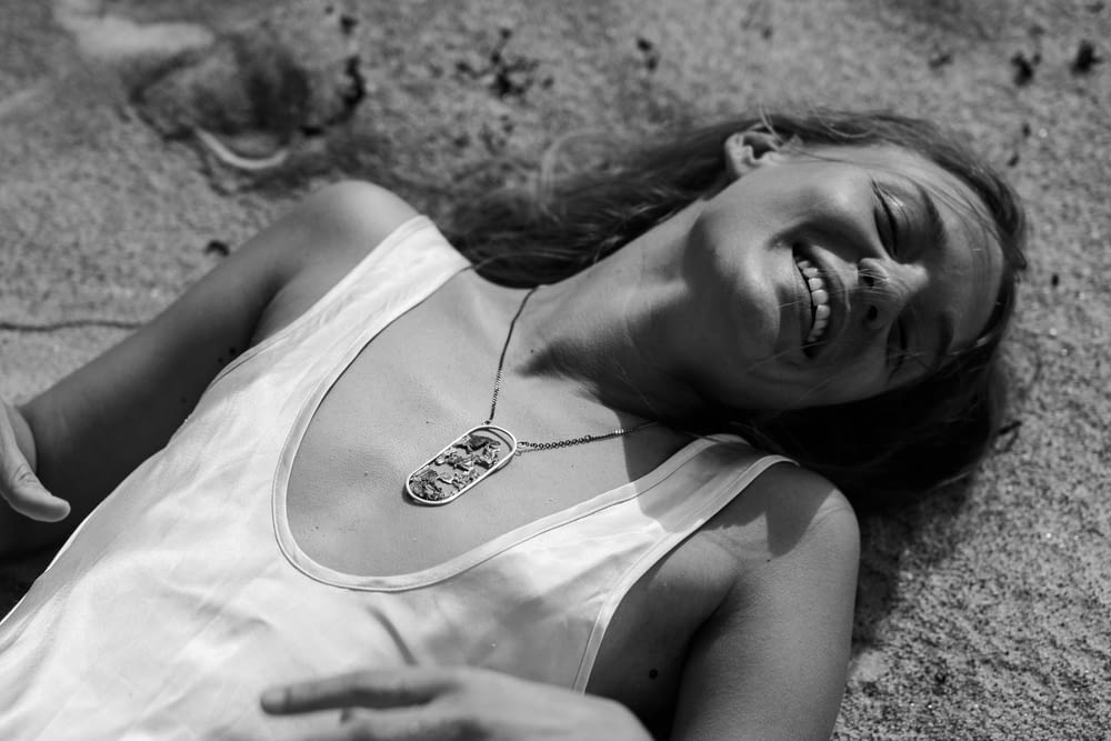 a woman laying on the ground wearing a necklace