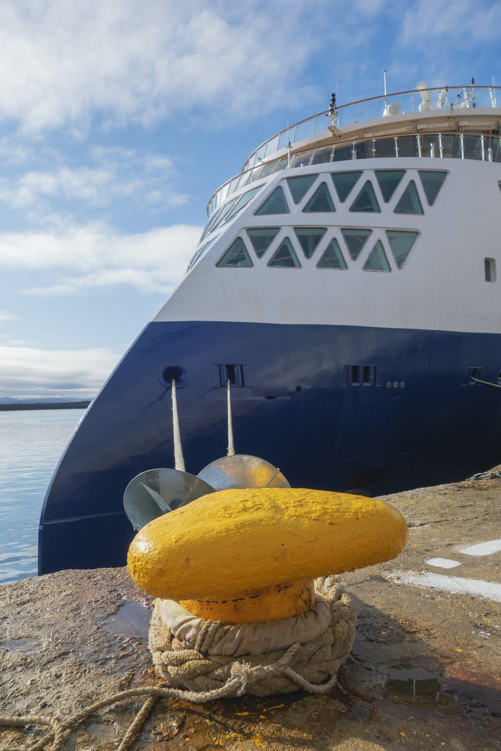 a yellow buoy sitting on the ground next to a large ship