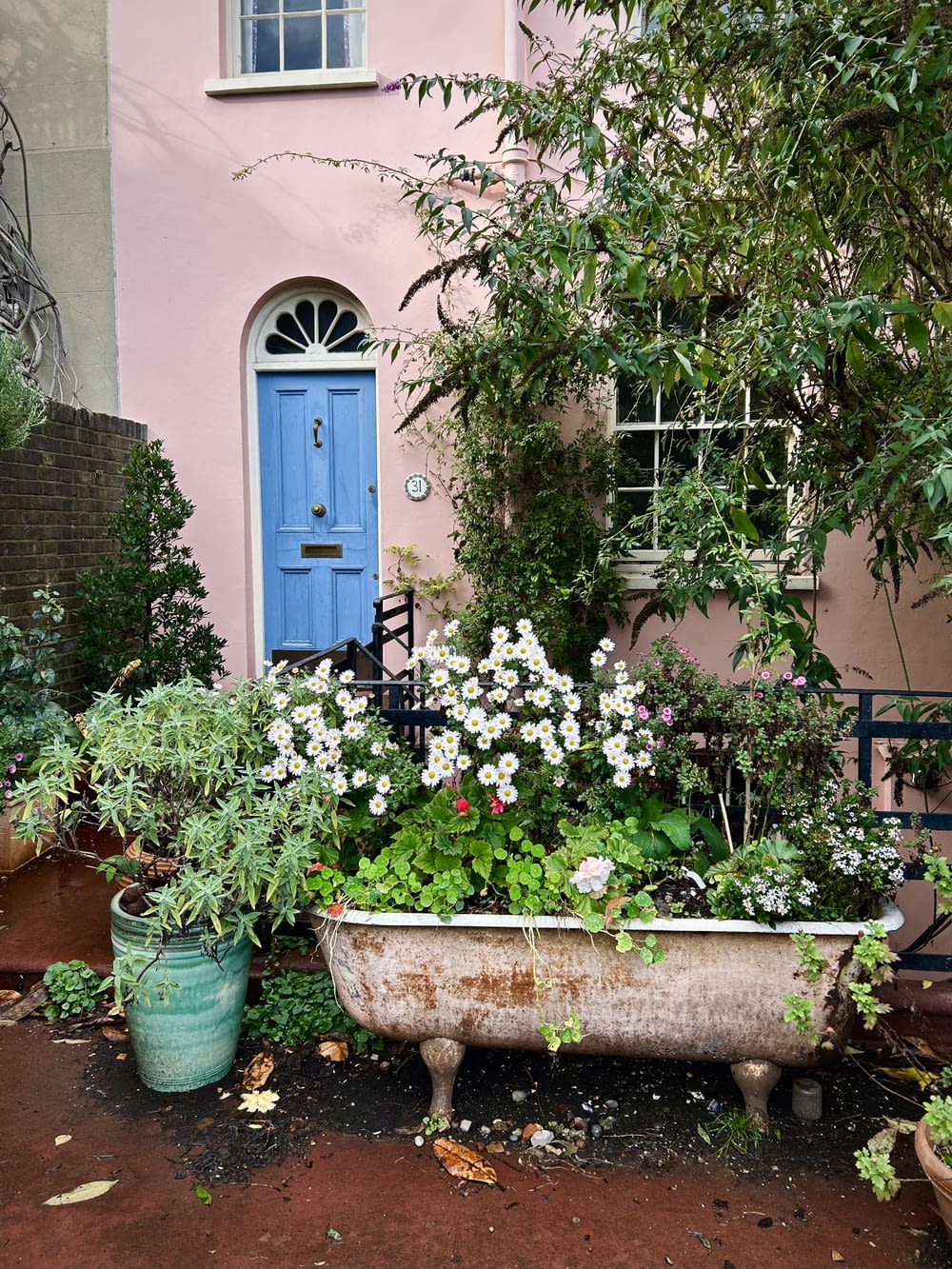 a bath tub filled with flowers next to a pink house