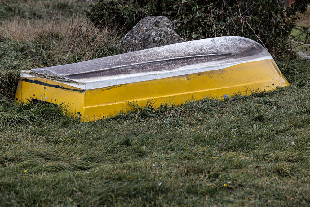 a yellow and silver boat sitting in the grass