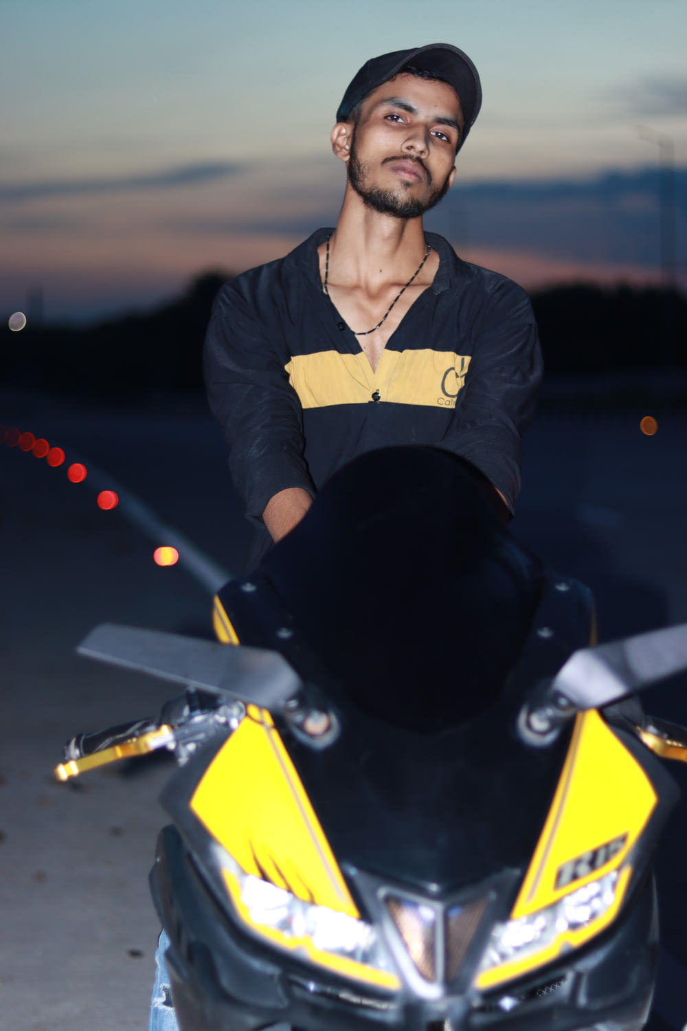 a man standing next to a yellow and black motorcycle