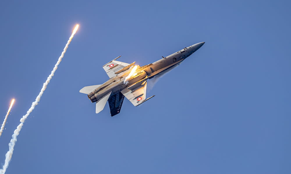 a fighter jet flying through a blue sky