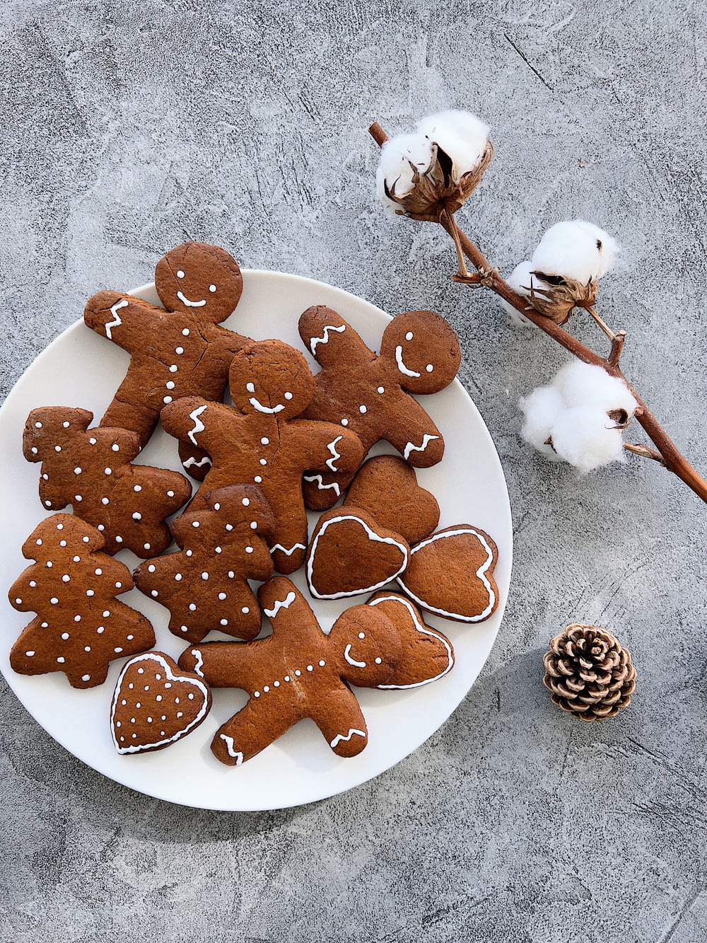 a plate of gingerbread cut - out cookies next to a cotton plant