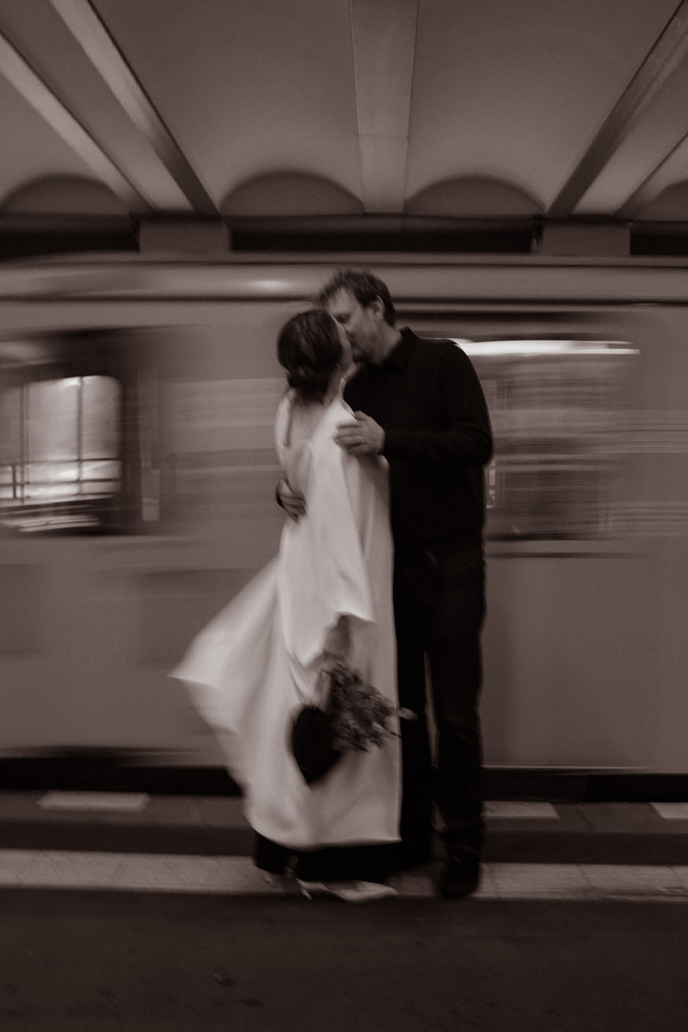 a man and a woman kissing in front of a train