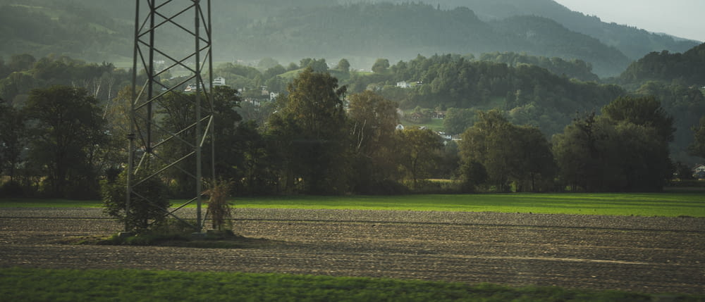 a power line in a field with mountains in the background