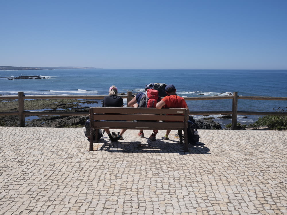 a group of people sitting on top of a wooden bench