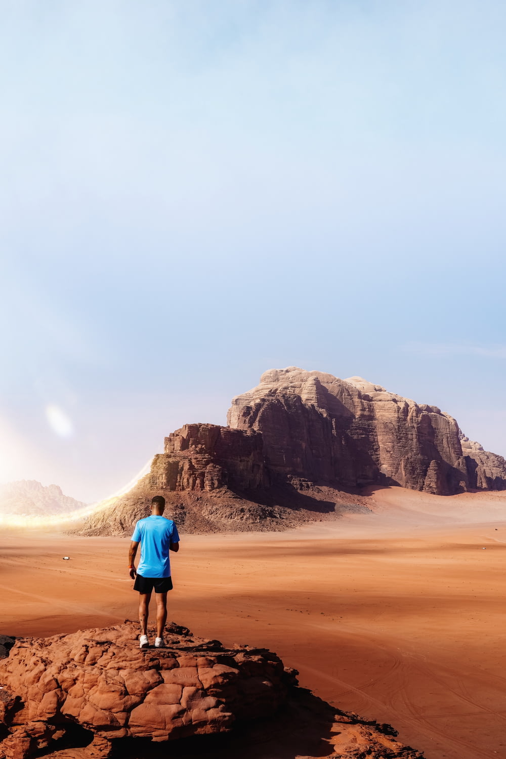 a man standing on a rock in the middle of a desert