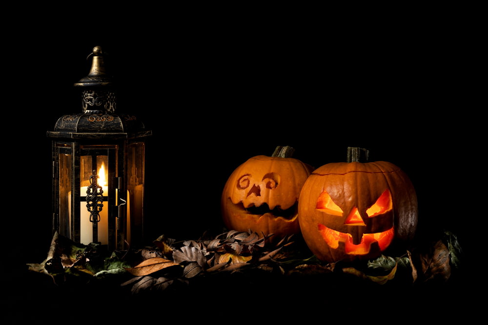 two carved pumpkins sitting next to a lantern