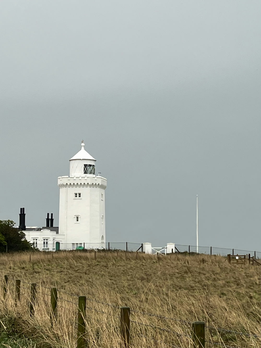 a white lighthouse on top of a grassy hill