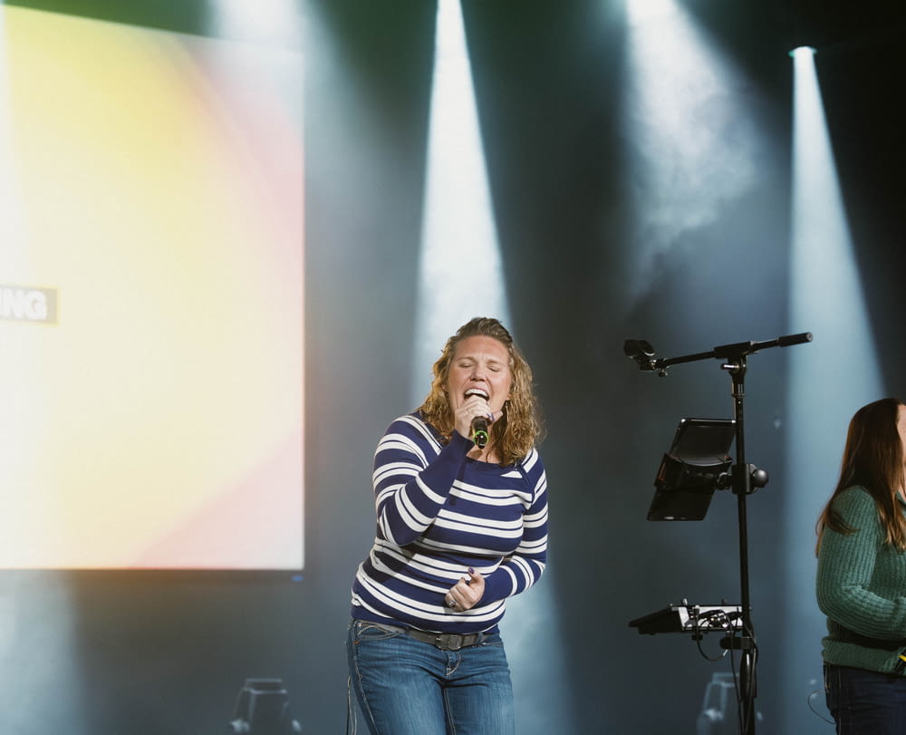 a woman standing on a stage singing into a microphone
