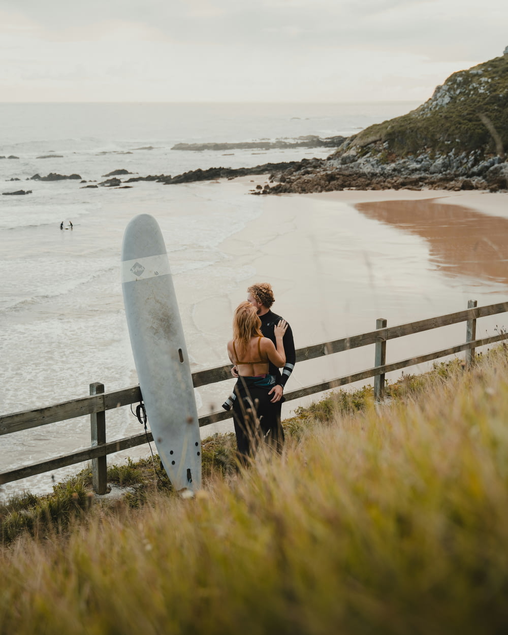 a man and a woman standing next to a surfboard