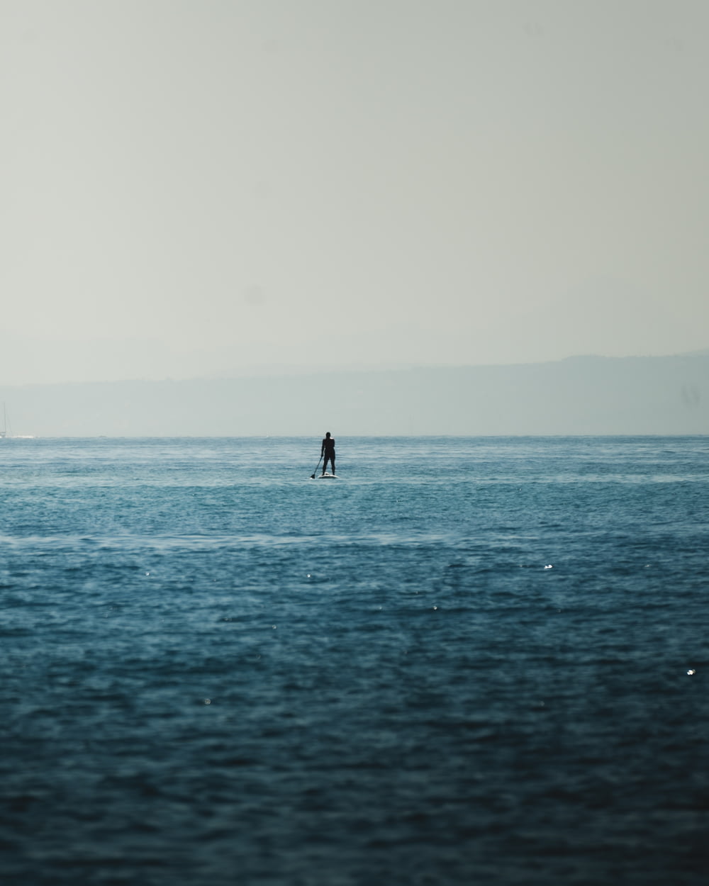 a person standing on a surfboard in the middle of the ocean