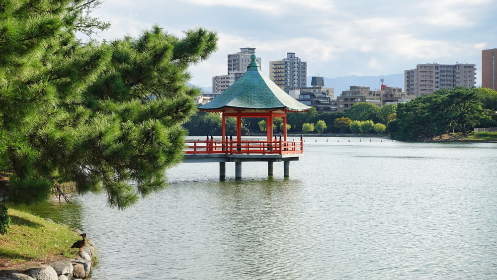 a gazebo in the middle of a lake with a city in the background