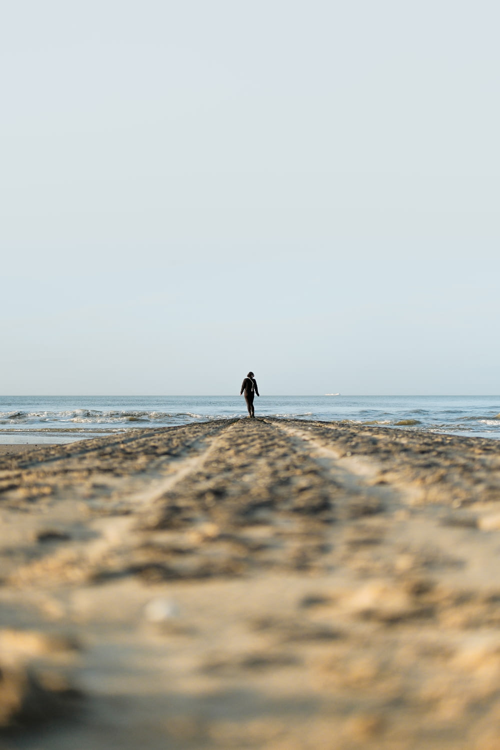 una persona sola che cammina su una spiaggia vicino all'oceano