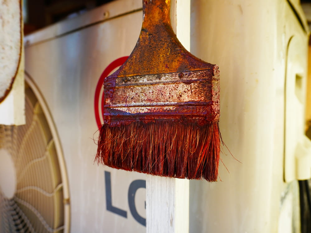 a rusted brush hanging from the side of a building