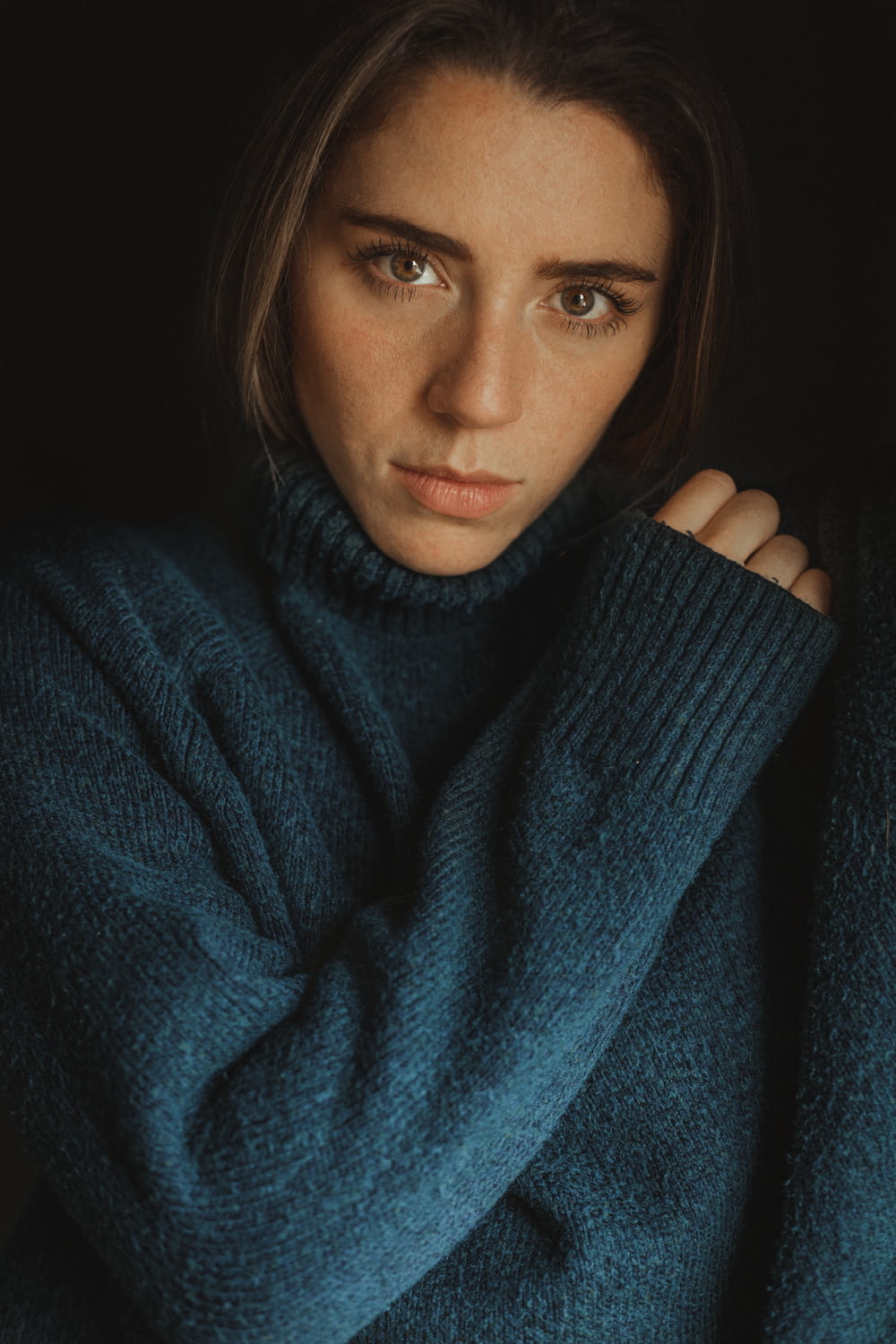 a woman in a blue turtle neck sweater
