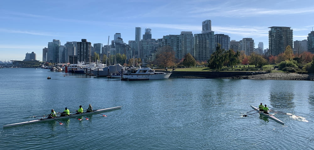 a group of people rowing on a lake in front of a city