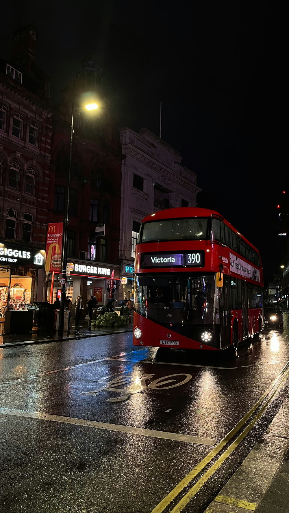 Un autobús rojo de dos pisos conduciendo por una calle de noche