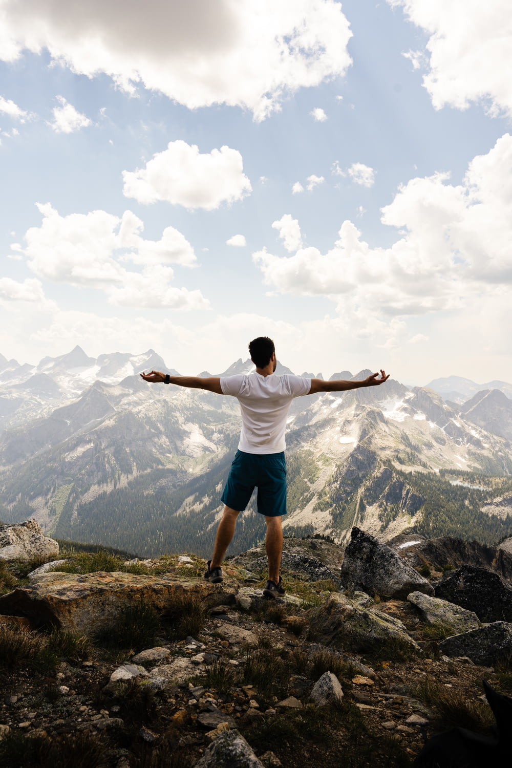 a man standing on top of a mountain with his arms outstretched