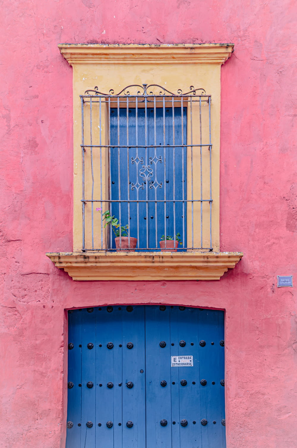 a pink building with a blue door and a window
