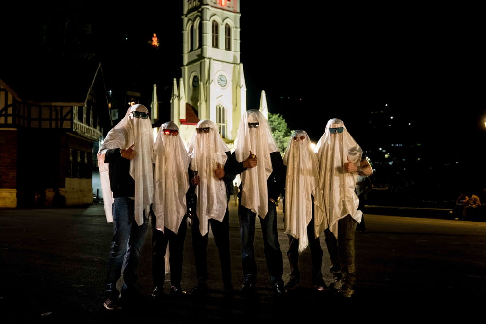a group of people dressed in white standing in front of a church