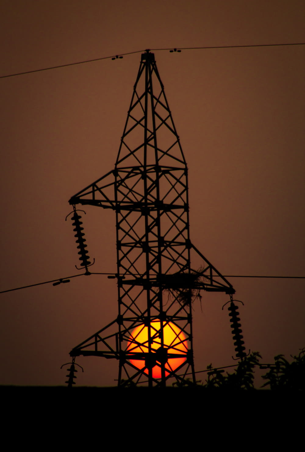 the sun is setting behind a power line tower