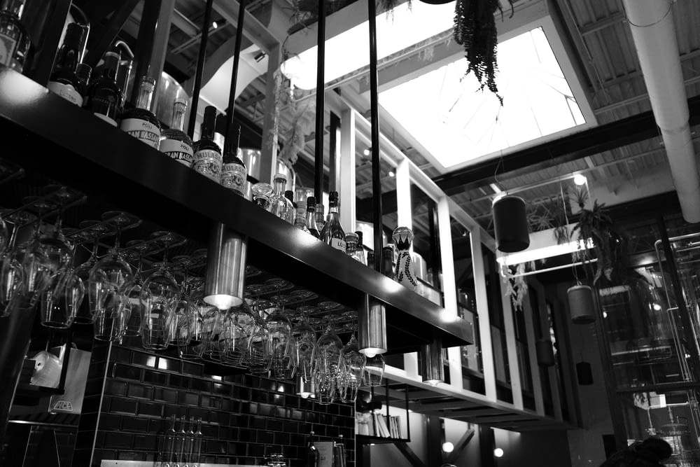 a black and white photo of a bar filled with wine glasses