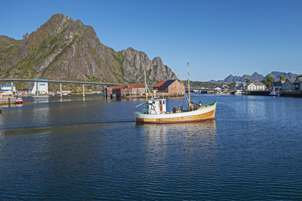 a small boat in a body of water with mountains in the background