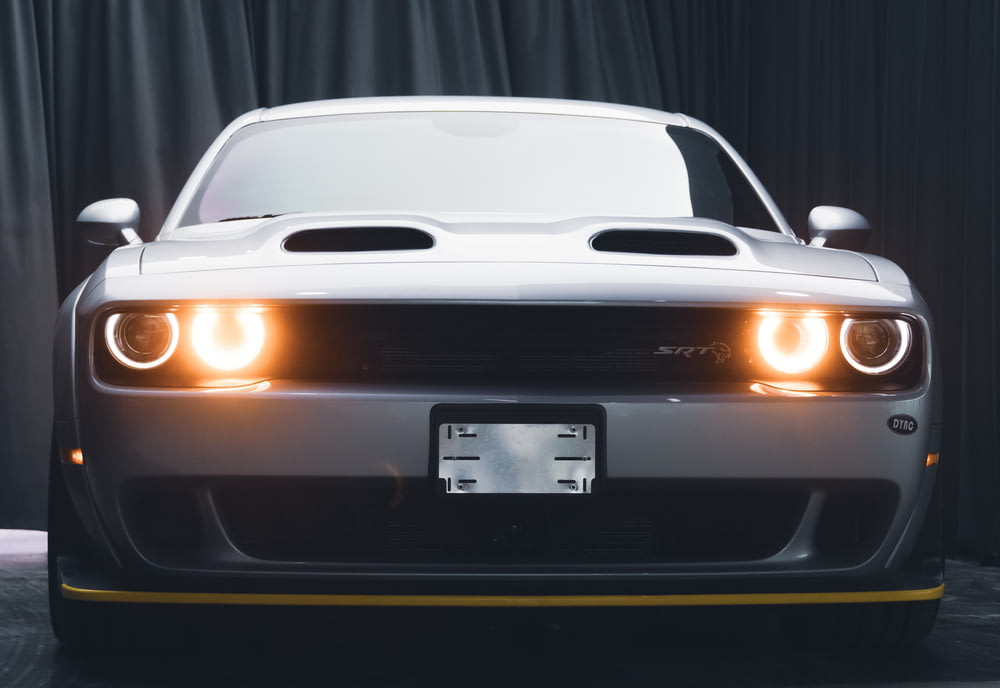 the front of a white sports car with its lights on