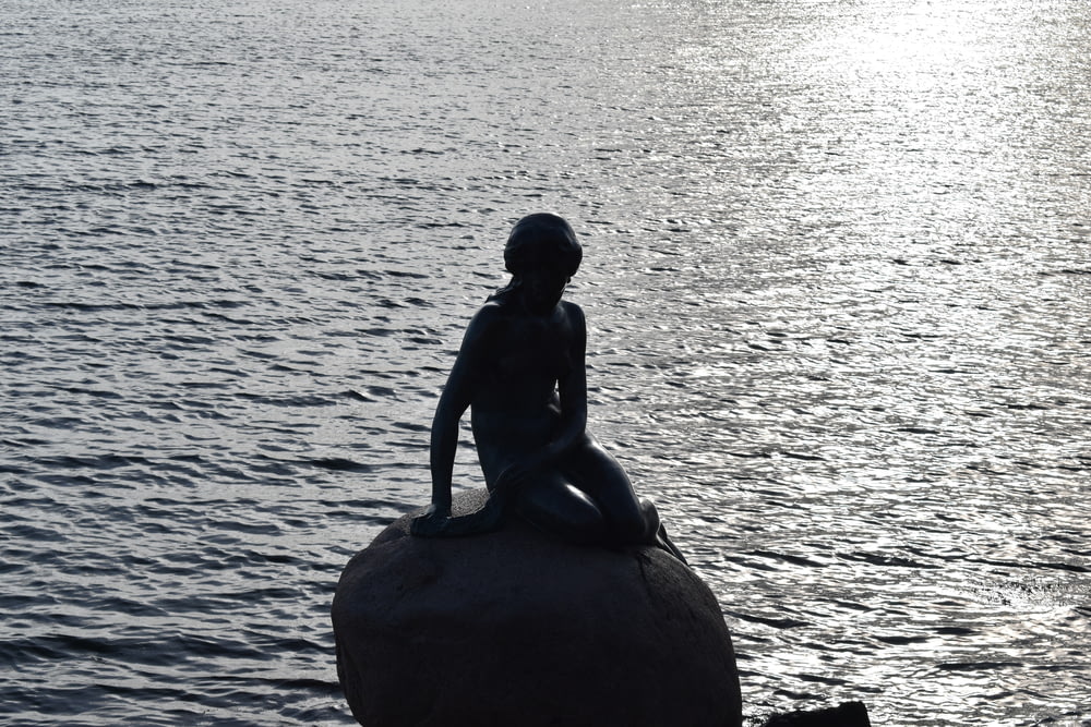 a statue of a person sitting on top of a rock