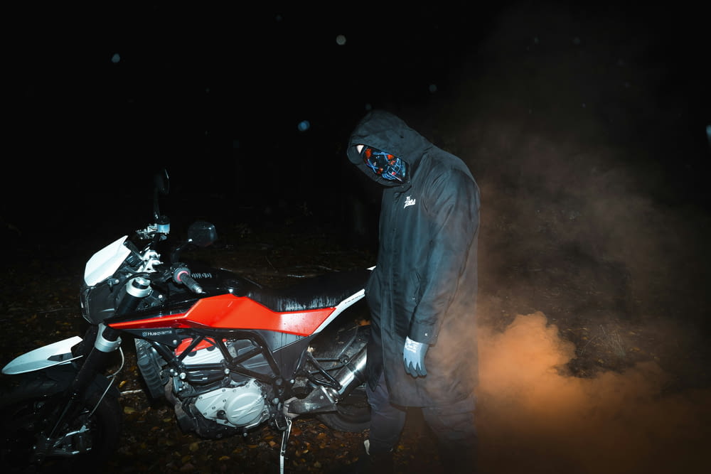 a man standing next to a motorcycle in the dark