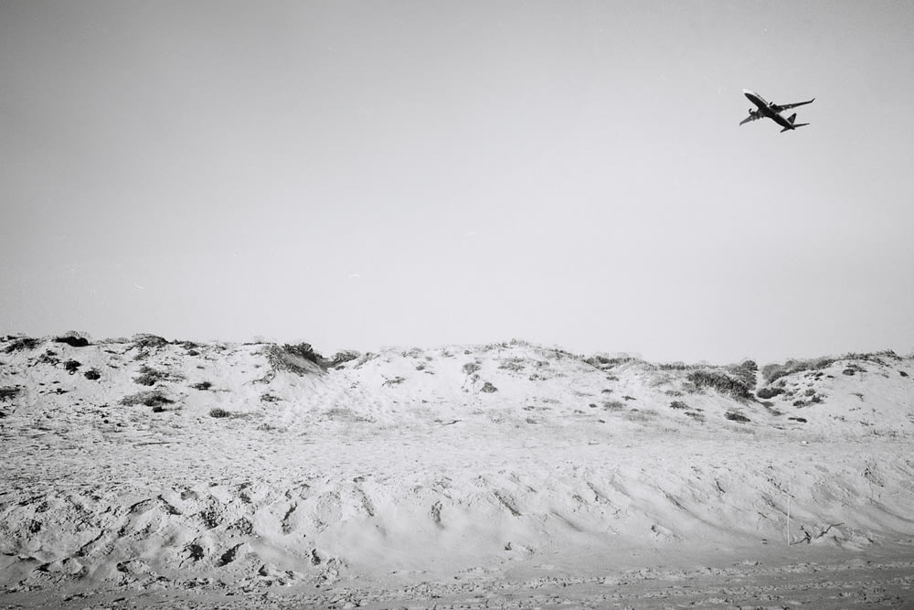 an airplane is flying over a snowy hill