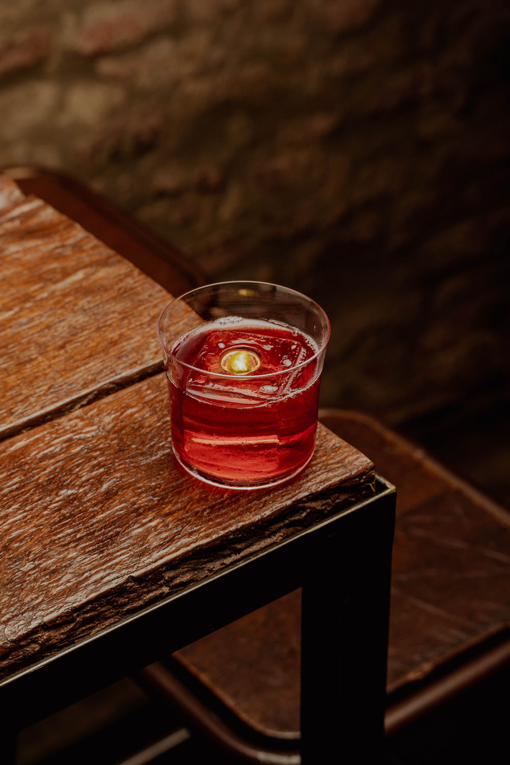 a glass of liquid sitting on top of a wooden table